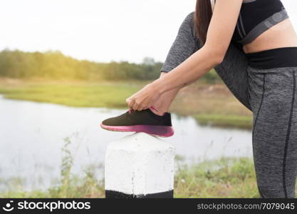 woman tying shoe laces. Female sport fitness runner getting ready for jogging outdoors on road in park