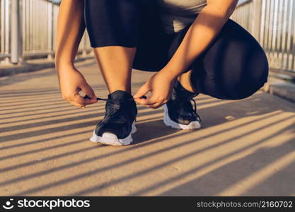 woman tying shoelaces on a footbridge