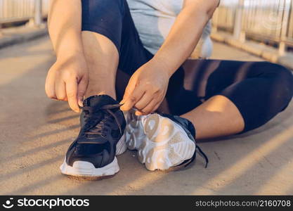 woman tying shoelaces on a footbridge