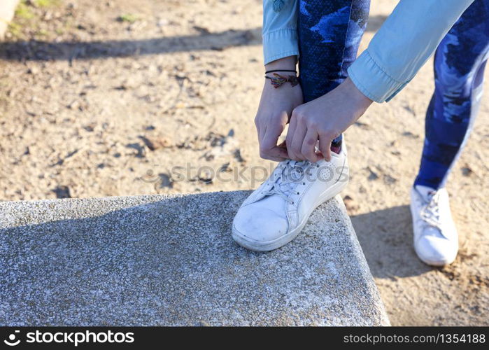 Woman tying the shoelaces on running track on a step