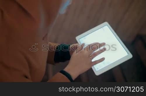 Woman typing chat message on tablet computer on the way upstairs in underground