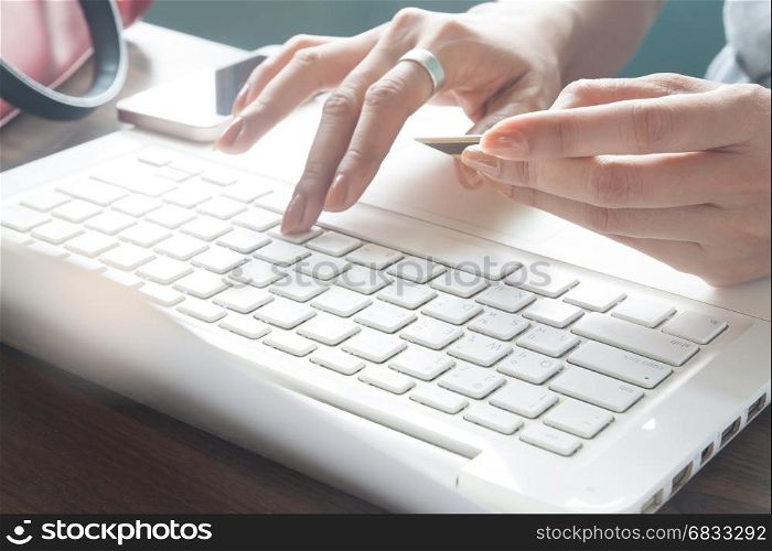 Woman typing on laptop keyboard and holding credit card, Online marketing concept