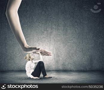 Woman under pressure. Young businesswoman pressed by big powerful hand