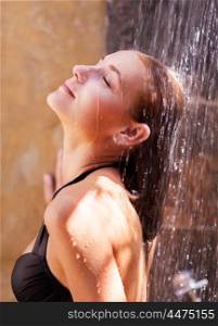 Woman under refreshing shower, enjoying cold water drops after beach, closing eyes of pleasure, summer vacation