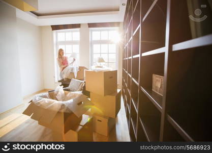 Woman unpacking lamp from moving box at new house