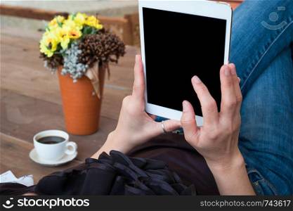 woman uses tablet while relaxing at home with coffee on wooden floor