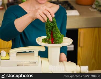 Woman using a centrifuge machine to prepare a detox juice.