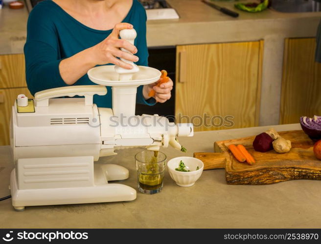 Woman using a centrifuge machine to prepare a detox juice.