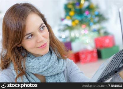 Woman using a laptop by her Christmas tree