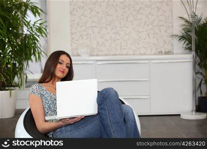 Woman using a laptop in a comfortable chair