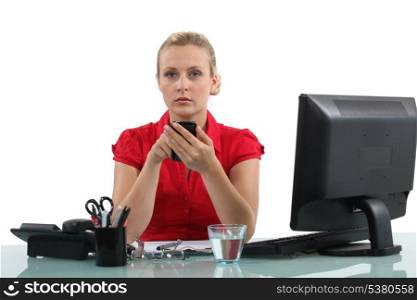 Woman using a mobile phone at her office desk