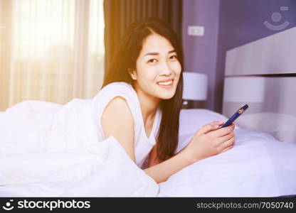 woman using a phone in her hand on bed in the bedroom