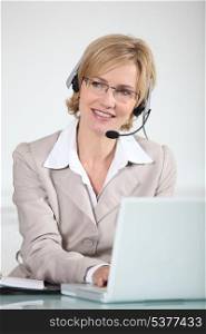 Woman using a telephone headset at a laptop computer