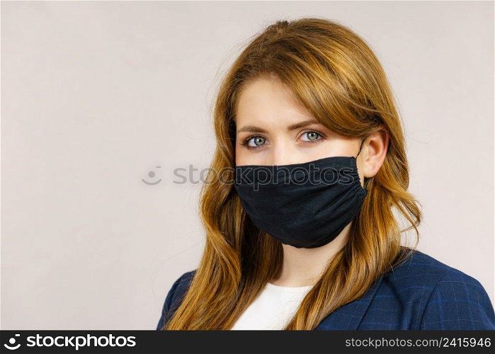 Woman using black protective reusab≤face mask, covering mouth. Coronavirus prevention. Hea<h and safety.. Woman using protective face mask.