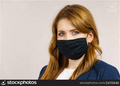 Woman using black protective reusab≤face mask, covering mouth. Coronavirus prevention. Hea<h and safety.. Woman using protective face mask.