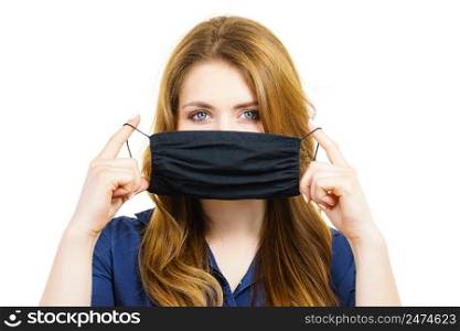 Woman using black protective reusable face mask, covering mouth. Coronavirus prevention. Health and safety.. Woman using protective face mask.