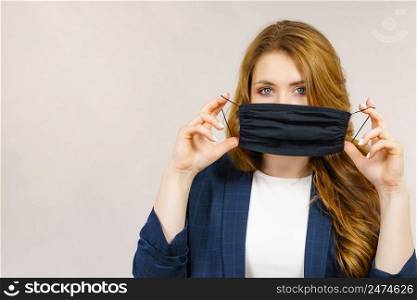 Woman using black protective reusable face mask, covering mouth. Coronavirus prevention. Health and safety.. Woman using protective face mask.