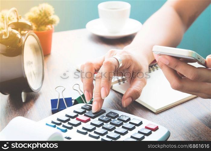 Woman using calculator and verifies mobile banking on smartphone