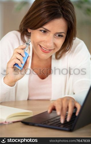 woman using computer while smoking e-cigarette