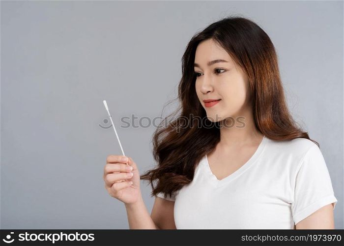woman using coronavirus(covid-19) rapid antigen self test kit (atk) at home with a cotton nasal swab