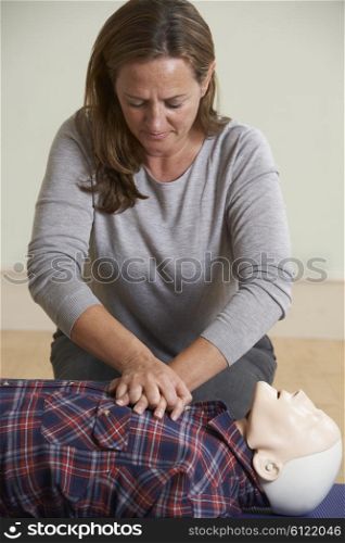 Woman Using CPR Technique On Dummy In First Aid Class