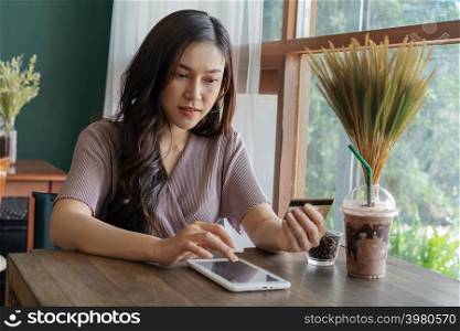 woman using credit card to shopping online with tablet at the cafe