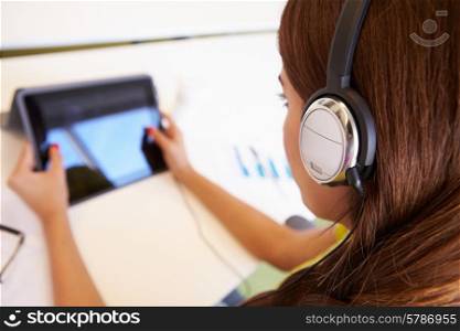 Woman Using Digital Tablet And Headphones In Design Studio