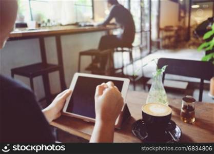 Woman using digital tablet at the table with cup of hot latte in the cafe