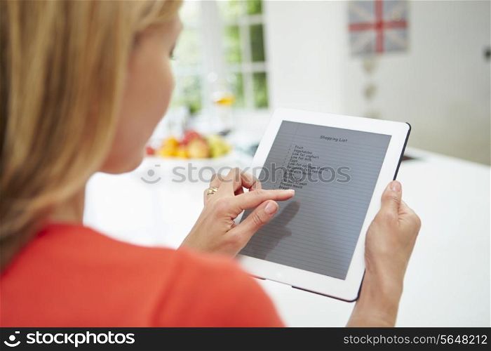 Woman Using Digital Tablet To Write Shopping List At Home