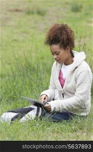 Woman Using Digital Tablet Whilst Hiking In Countryside