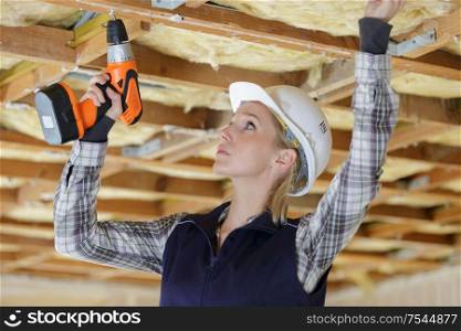 woman using drill on indoor construction site