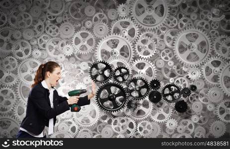 Woman using drill. Young businesswoman using drill to fix gears mechanism