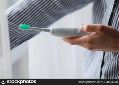 woman using electric toothbrush at home. technology and health care.. woman using electric toothbrush at home. technology and health care