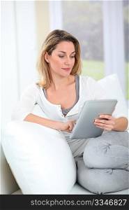 Woman using electronic tab sitting in couch