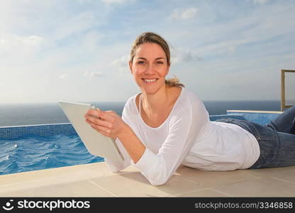 Woman using electronic tablet by swimming pool