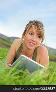 Woman using electronic tablet laying in grass