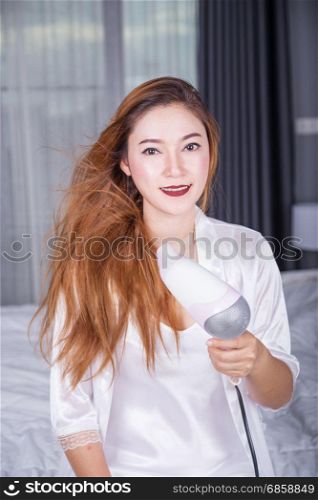 woman using hair dryer in the bedroom