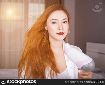 woman using hair dryer in the bedroom with soft light