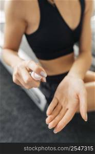 woman using hand sanitizer before working out gym