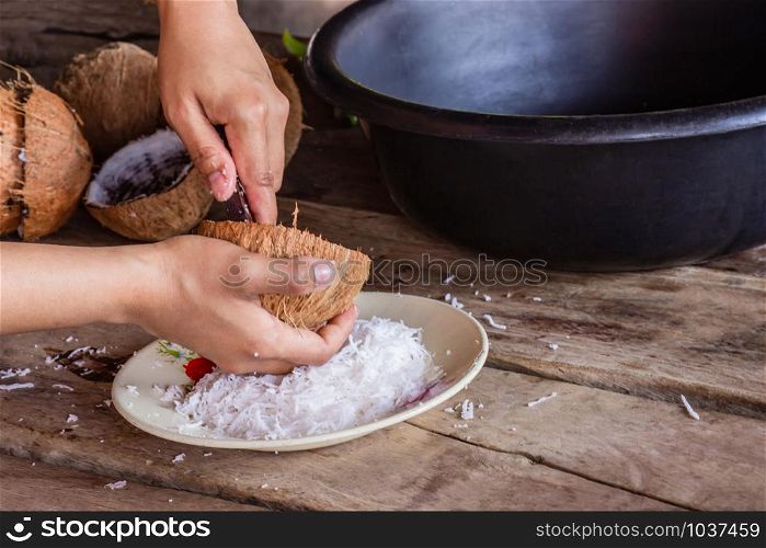 Woman using hand scraping coconut put the container for make dessertand food.