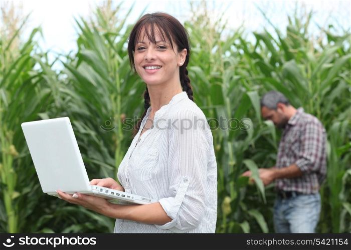 Woman using her laptop in a field of crops