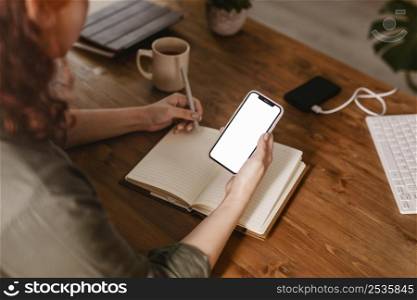 woman using her smartphone writing down agenda