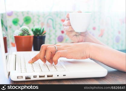 Woman using laptop and drinking coffee at home, Work at home concept