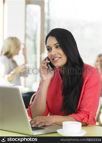 Woman Using Laptop And Mobile Phone In Cafe