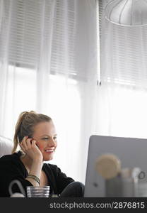 Woman using laptop and mobile phone sitting at desk low angle view