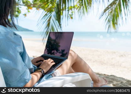 Woman using laptop and smartphone to work study in vacation cady at beach background. Business, financial, trade stock maket and social network concept.