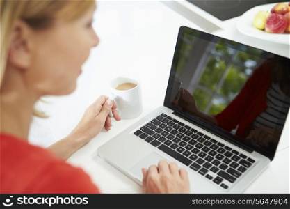 Woman Using Laptop At Home In Kitchen