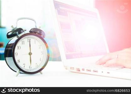 Woman using laptop computer on modern white working space with classic alarmclock, Work and Education concept