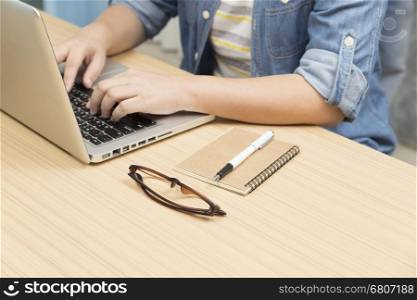 woman using laptop computer with eyeglasses, notebook and pen for use as working concept