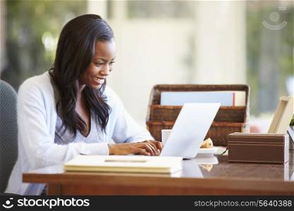 Woman Using Laptop On Desk At Home